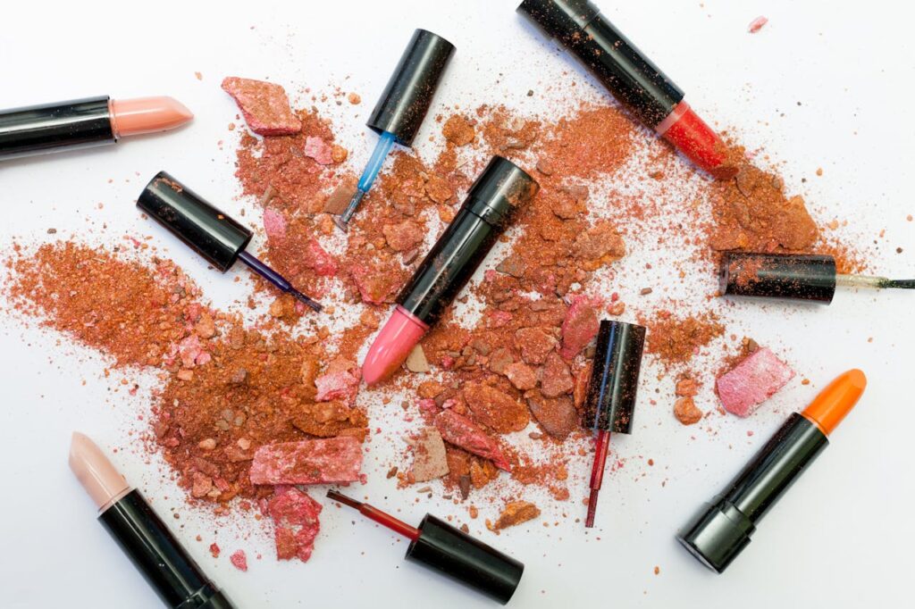pexels-photo-1377034 Colorful scattered makeup products including lipsticks and crushed powders on a white background.