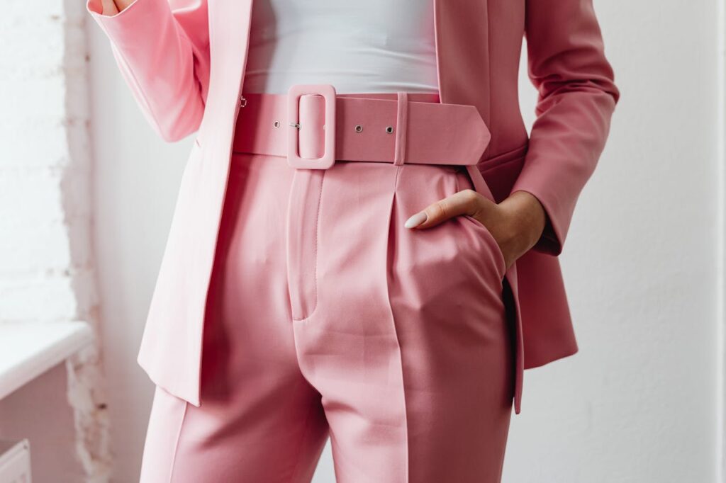 pexels-photo-7680206 Close-up of a woman in a stylish pink suit, hand in pocket.